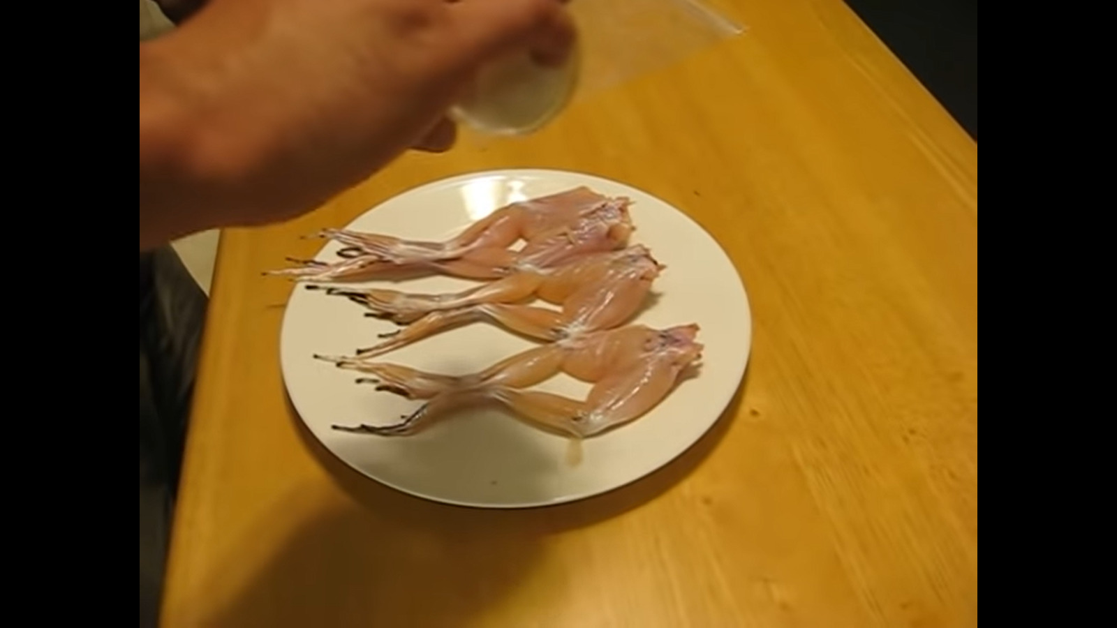 adding salt to frogs legs on plate